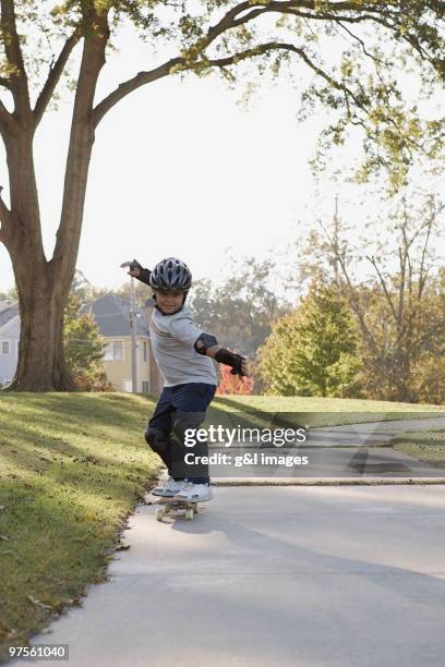 boy skateboarding on sidewalk - coudière photos et images de collection