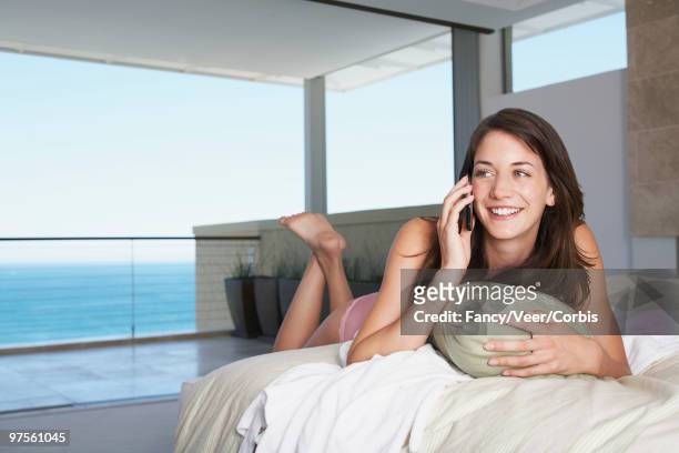 young woman using a cell phone - woman lying on stomach with feet up fotografías e imágenes de stock