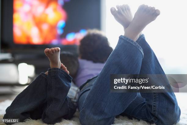 mother and son watching television - woman lying on stomach with feet up fotografías e imágenes de stock