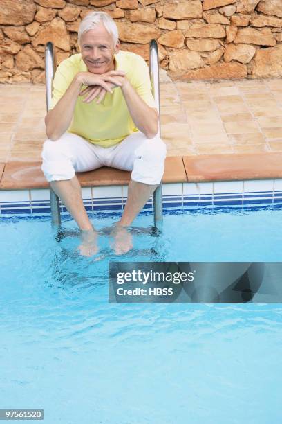 man soaking feet in swimming pool - khaki pants sitting stock pictures, royalty-free photos & images
