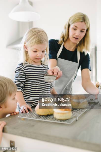 scandinavian family making semla buns using powder suger - flour sifter stock pictures, royalty-free photos & images