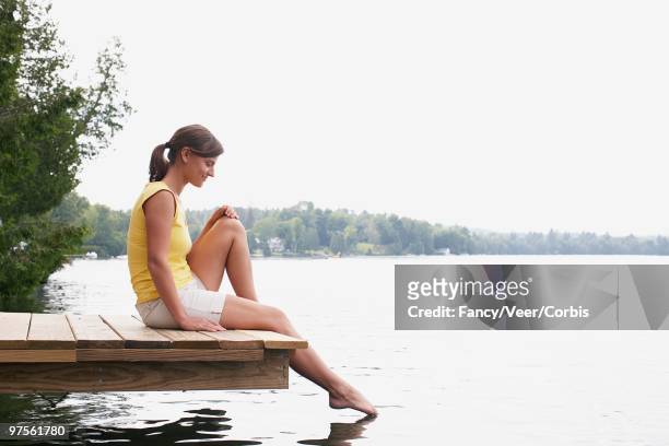 woman sitting on dock - superexposto - fotografias e filmes do acervo