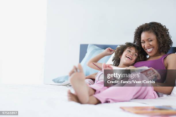 mother and daughter reading together - kids feet in home stock-fotos und bilder