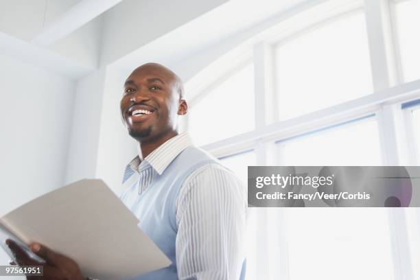 businessman holding documents and smiling - superexposto - fotografias e filmes do acervo