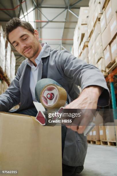 warehouse worker sealing box - tape dispenser stock pictures, royalty-free photos & images