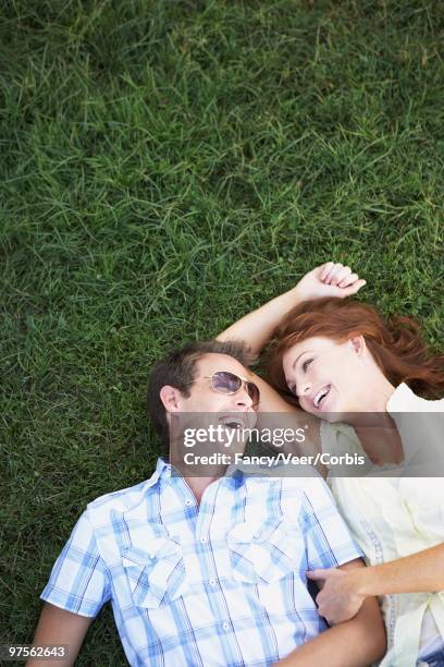 happy couple lying down in the grass - down blouse stock pictures, royalty-free photos & images