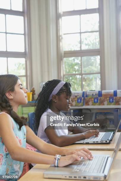 girl looking at classmate's computer screen - children only braided ponytail stock pictures, royalty-free photos & images