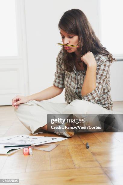 woman examining blueprints - fashion woman floor cross legged fotografías e imágenes de stock