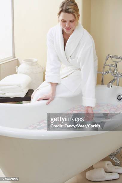 woman sitting on edge of clawfoot tub - floating faucet stock pictures, royalty-free photos & images