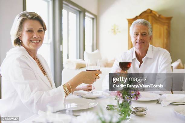 woman and man holding wine glasses - luxury home dining table people lifestyle photography people stock pictures, royalty-free photos & images