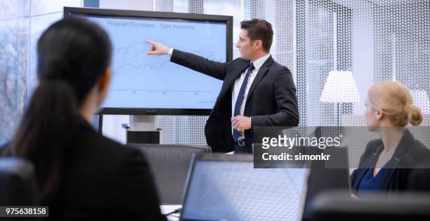 businessman explaining about graph on screen - blue coat stock pictures, royalty-free photos & images