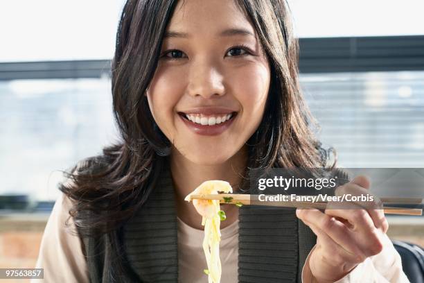 young woman eating with chopsticks - carboidrato componente di organismo vivente foto e immagini stock