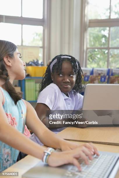girl looking at classmate's computer screen - children only braided ponytail stock pictures, royalty-free photos & images