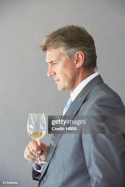 pensive businessman holding glass of wine - connoisseur stock pictures, royalty-free photos & images