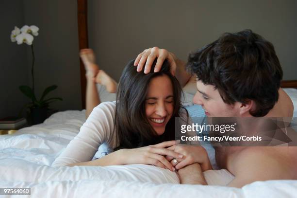 couple in bed - woman lying on stomach with feet up foto e immagini stock