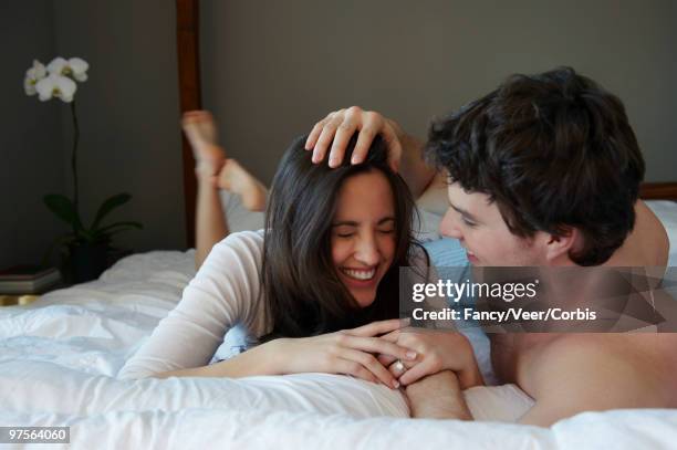 couple in bed - woman lying on stomach with feet up stock pictures, royalty-free photos & images