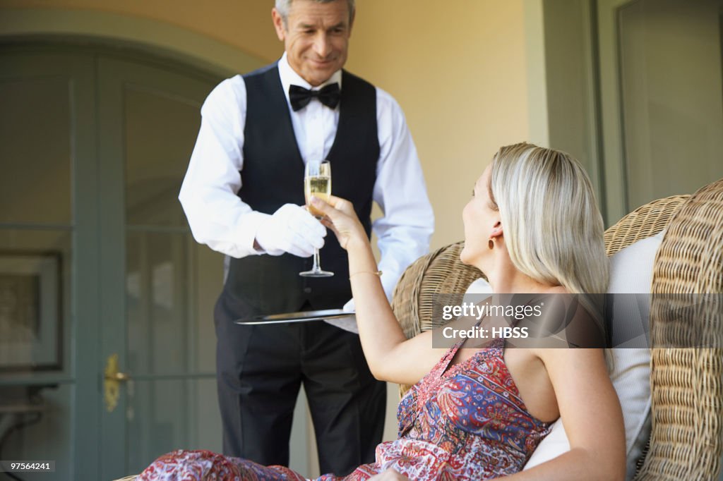 Waiter serving glass of champagne to woman