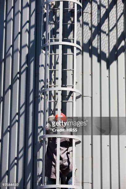 industrial worker climbing ladder on silo - vrachtruimte stockfoto's en -beelden