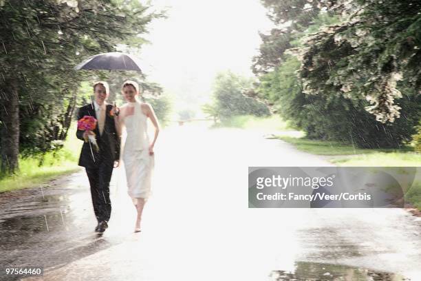 bride and bridegroom walking through rain - imagem super exposta - fotografias e filmes do acervo