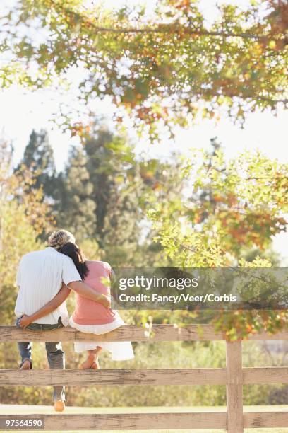 couple sitting together on a fence - imagem super exposta - fotografias e filmes do acervo