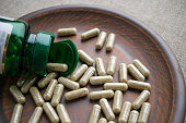 Close up biotin capsules and bottle on clay brown plate on burlap background