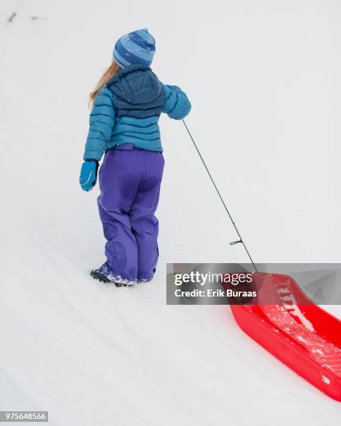 girl with red plastic sledge in the snow - erik buraas stock-fotos und bilder