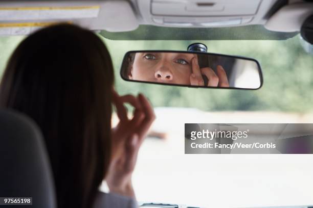 woman looking in a rear view mirror - rear view mirror eyes stock pictures, royalty-free photos & images