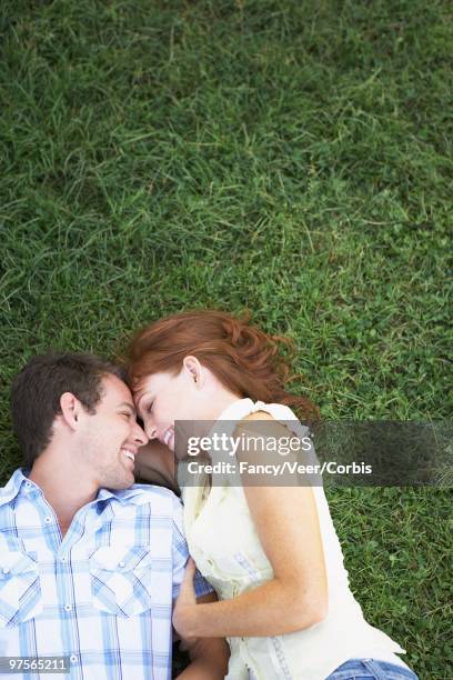 couple lying down in the grass - down blouse stockfoto's en -beelden