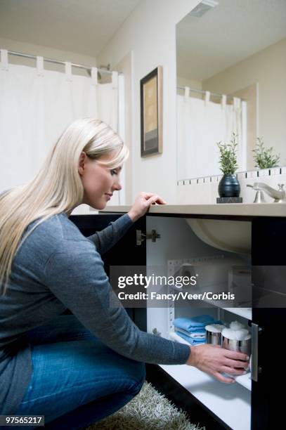 woman tidying bathroom cabinet - under sink foto e immagini stock