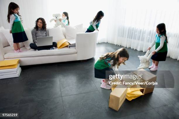 girl playing in living room while mother using laptop computer - fashion woman floor cross legged fotografías e imágenes de stock