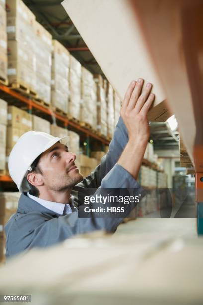 warehouse worker lifting box - vrachtruimte stockfoto's en -beelden