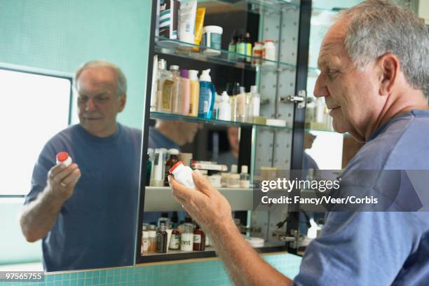 man holding medicine bottle - badezimmerschrank stock-fotos und bilder