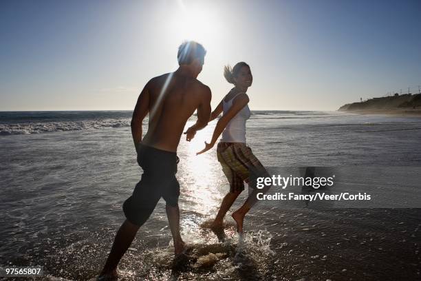 couple playing in water - veer stock pictures, royalty-free photos & images