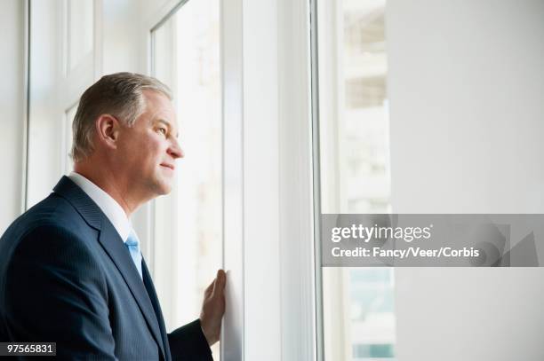 businessman looking out window - veer stock pictures, royalty-free photos & images