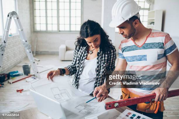 jonge vrouw en bouw werknemer kijken blauwdrukken - 2018 blueprint stockfoto's en -beelden