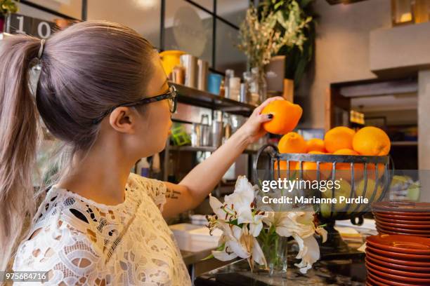 choosing an orange from a basket - ネーブルオレンジ ストックフォトと画像