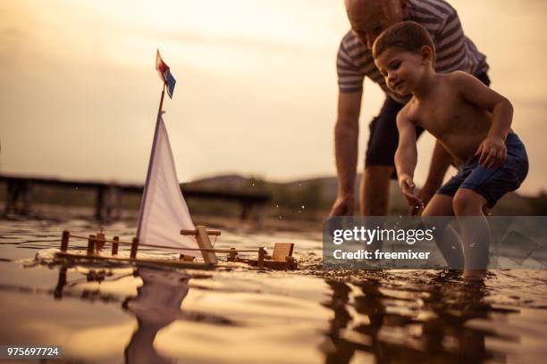 grand-père et son petit-fils l’embarcation ensemble - bateau à voile en famille photos et images de collection