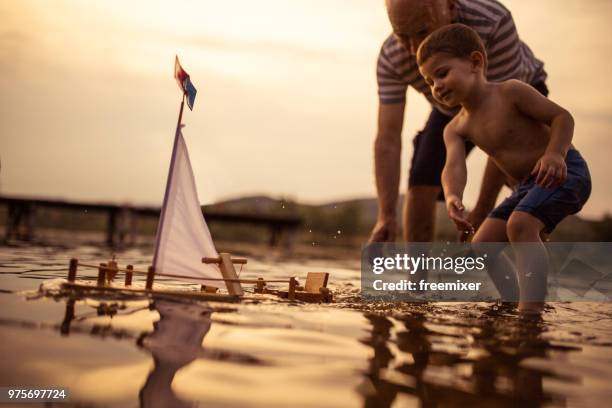 grandfather and grandson sailing the boat together - toy sailboat stock pictures, royalty-free photos & images