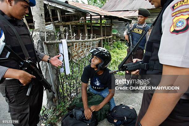 Indonesian police check a resident's identity card amid ongoing efforts to capture suspected militants in Pidie, Aceh on March 9, 2010. Indonesian...