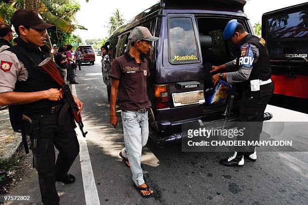 Indonesian police check a motorist's identity card amid ongoing efforts to capture suspected militants in Pidie, Aceh on March 9, 2010. Indonesian...