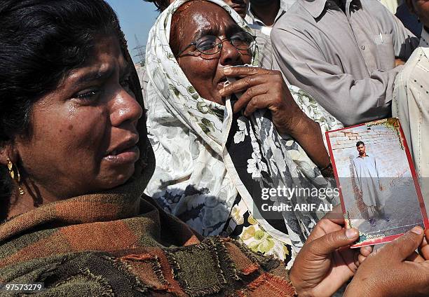 Pakistani woman, standing next to her mother, holds a picture of her brother at the site that went missing in Lahore�s latest suicide attack on a law...