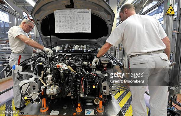 Audi employees work on the engine section of an Audi A3 automobile as it passes along the assembly line at the Audi AG factory in Ingolstadt,...