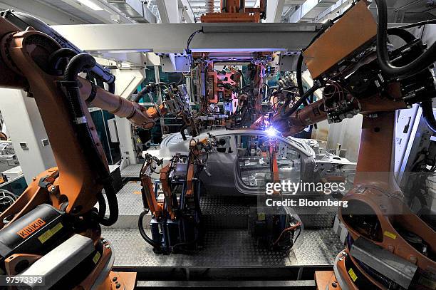 Robotics arms work on an Audi A5 automobile during the assembly process at the Audi AG factory in Ingolstadt, Germany, on Monday, March 8, 2010....