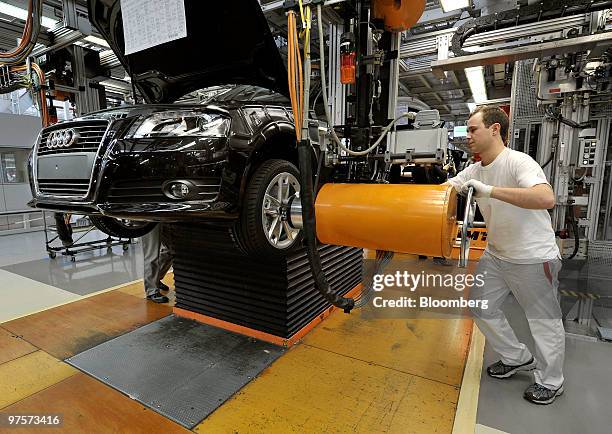 An Audi employee attaches a tire to an Audi A3 automobile as it passes along the assembly line at the Audi AG factory in Ingolstadt, Germany, on...