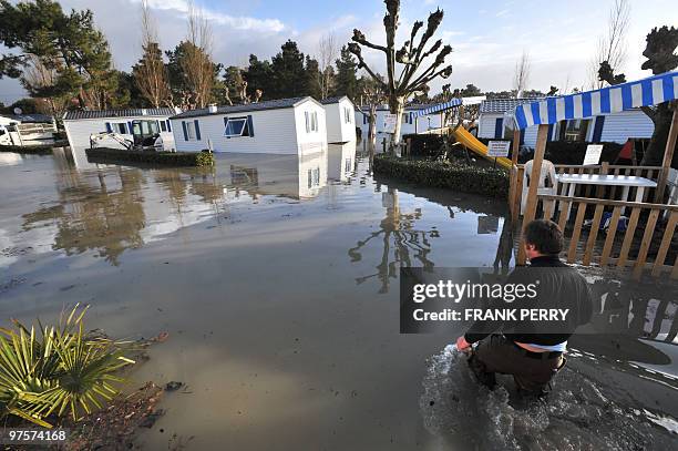 Man walks on February 28, 2010 on a flooded camping site, as a result of heavy floods overnight, in La Faute-sur-Mer, western France.Dubbed...