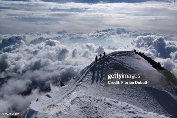 three people at the top of a snow-capped mountain. - florian schweizer stock-fotos und bilder