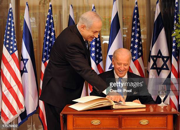 Israeli Prime Minister Benjamin Netanyahu helps US Vice President Joe Biden as he signs the guestbook at the Prime Minister's residence on March 9,...