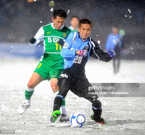 China's Beijing Guoan midfielder Yan Xiangchuang battles for the ball with Japanese club Kawasaki Frontale midfielder Junichi Inamoto under heavy...