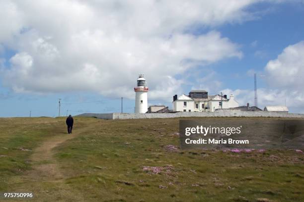 solitary irishman walking at loop head lighthouse - irishman stockfoto's en -beelden