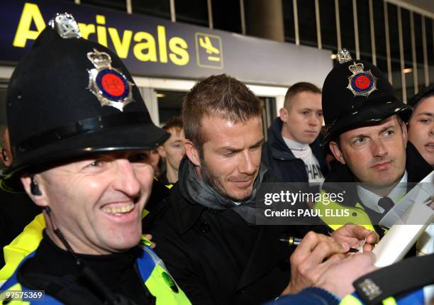 Milan's English midfielder David Beckham signs autographs as he arrives at Manchester Airport in Manchester, north-west England, on March 9, 2010...